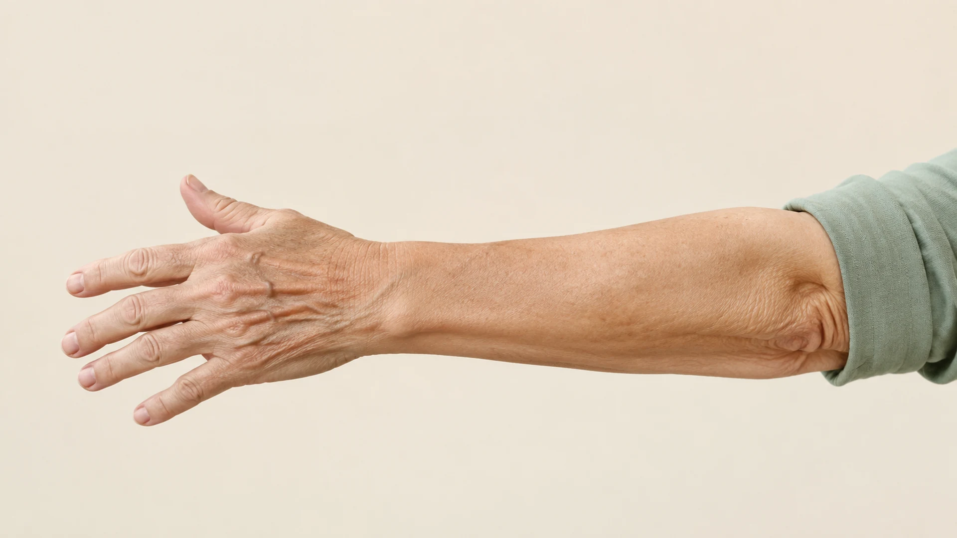 Detalle de un antebrazo y una mano extendidos sobre un fondo marfil